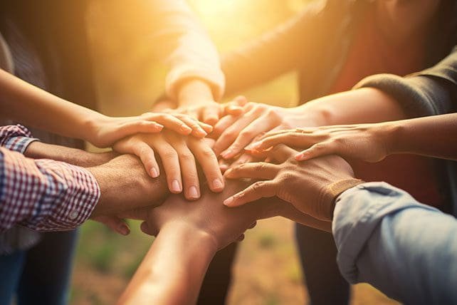 Members joining hands together to represent cooperation and shared commitment